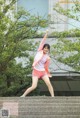 A woman in pink shorts and a pink jacket is standing on some steps.