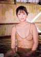 A woman in a brown bathing suit is standing in the water.