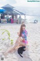 A woman sitting on the beach with a cat.