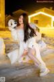 A woman in a white coat is sitting in the snow.