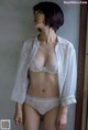 A woman wearing a white bra and panties standing in front of a mirror.
