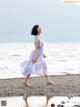 A woman in a blue dress walking on the beach.