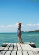 A woman standing on a wooden dock looking out at the ocean.