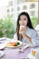 A woman sitting at a table with a plate of food and a glass of milk.