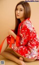 A woman in a red kimono sitting on the floor.