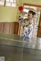 A woman in a kimono playing ping pong.