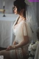 A woman in a wedding dress sitting on a bed.