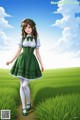 A girl in a green dress is walking through a field.