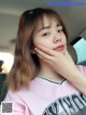 A woman sitting in the back seat of a car with her hand on her chin.