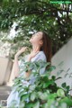 A woman in a blue and white striped dress standing under a tree.